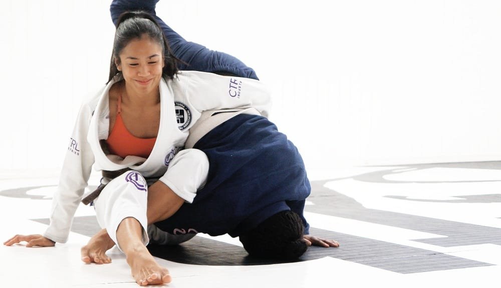 Girl sparring with a man in BJJ